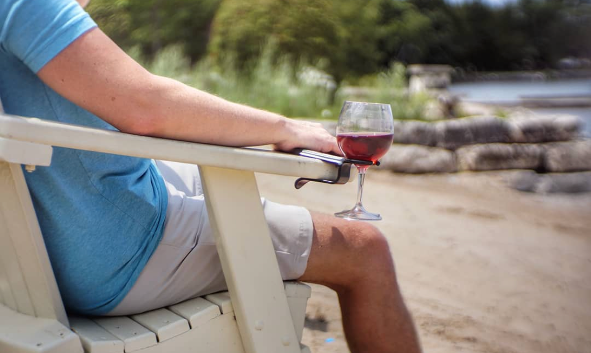 A man sitting with his wine holder on the beach